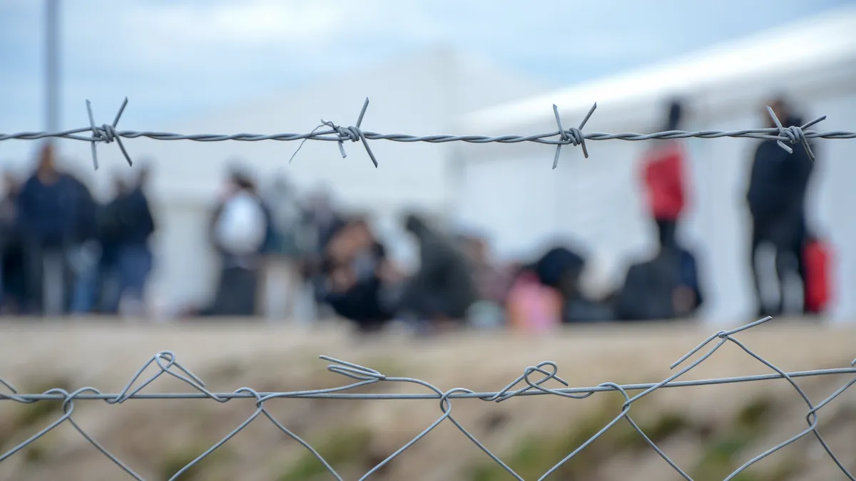 Migrants behind a chain-link fence