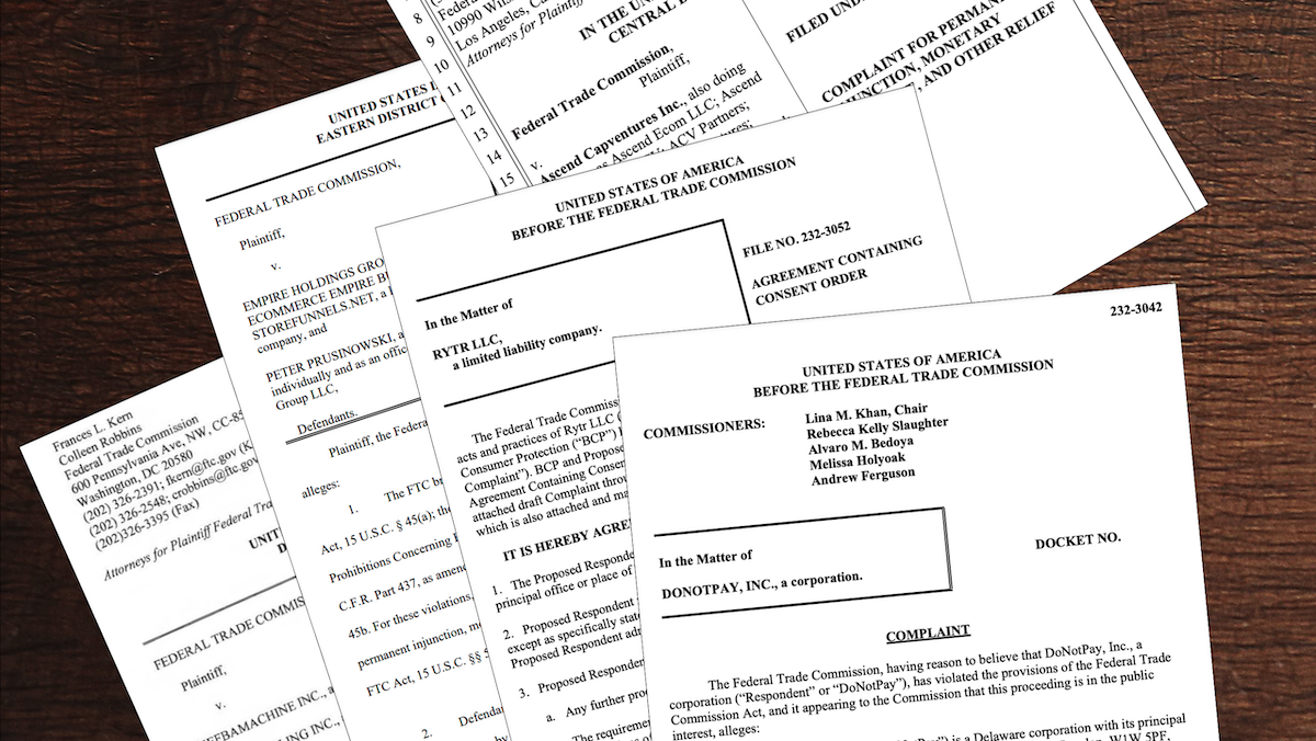 Several legal documents from the Federal Trade Commission are spread out on a wooden surface.