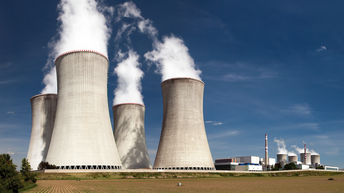 Nuclear power plant cooling towers emitting steam into the sky.